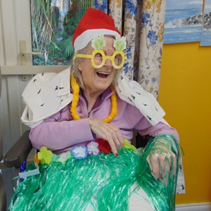 Happy resident celebrating Julymas with Christmas hat and grass skirt