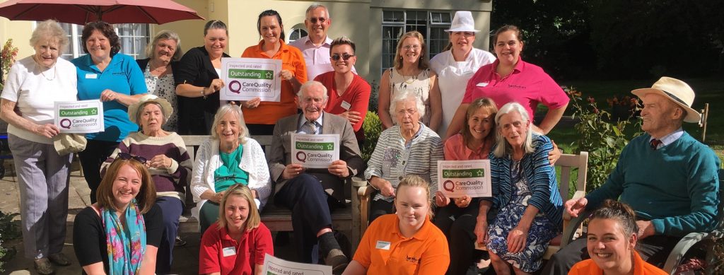 Tegfield staff and residents celebrating outstanding CQC result in the garden