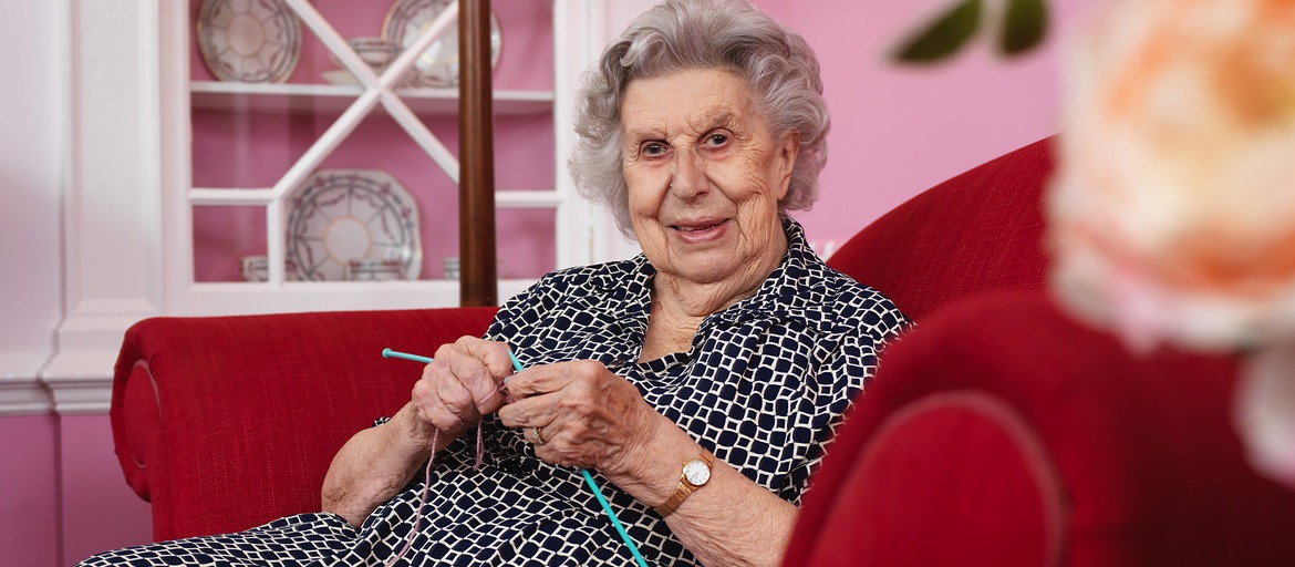 Resident knitting in cosy chair at Woodlands House