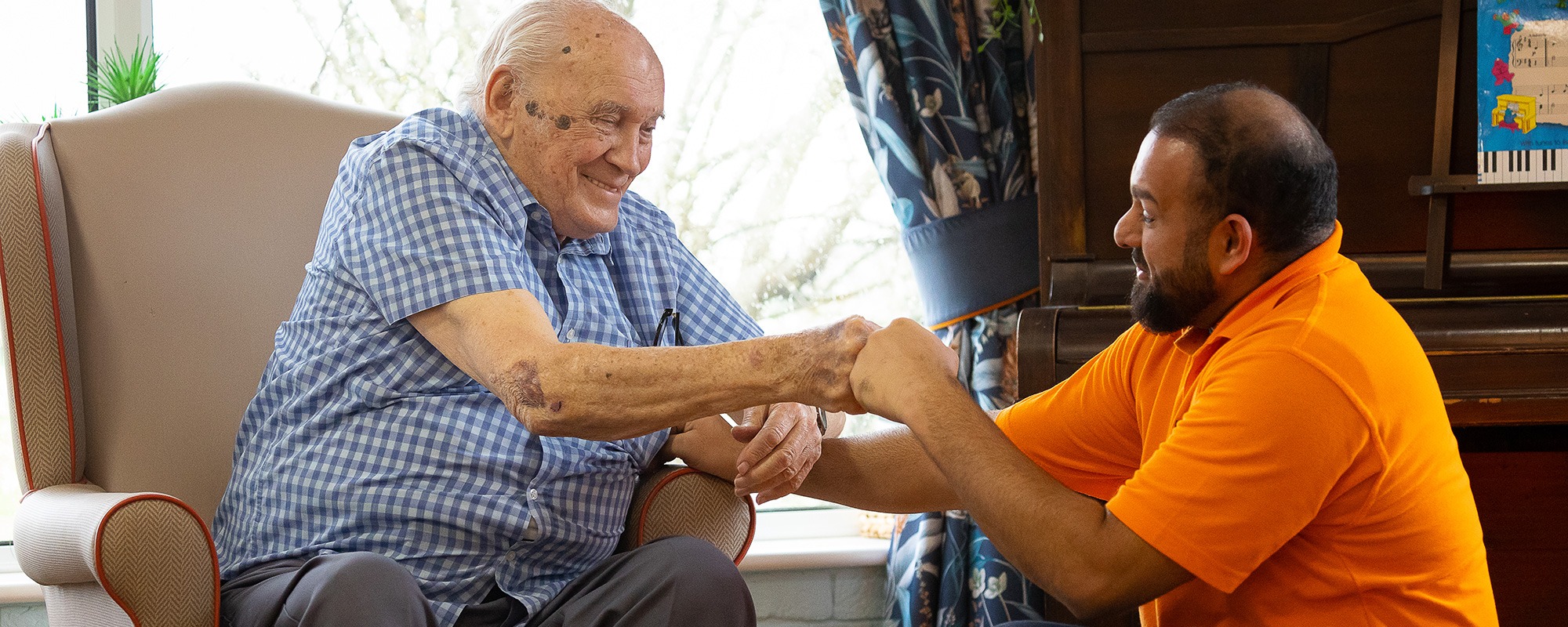 Care worker fist bumps with resident help and advice
