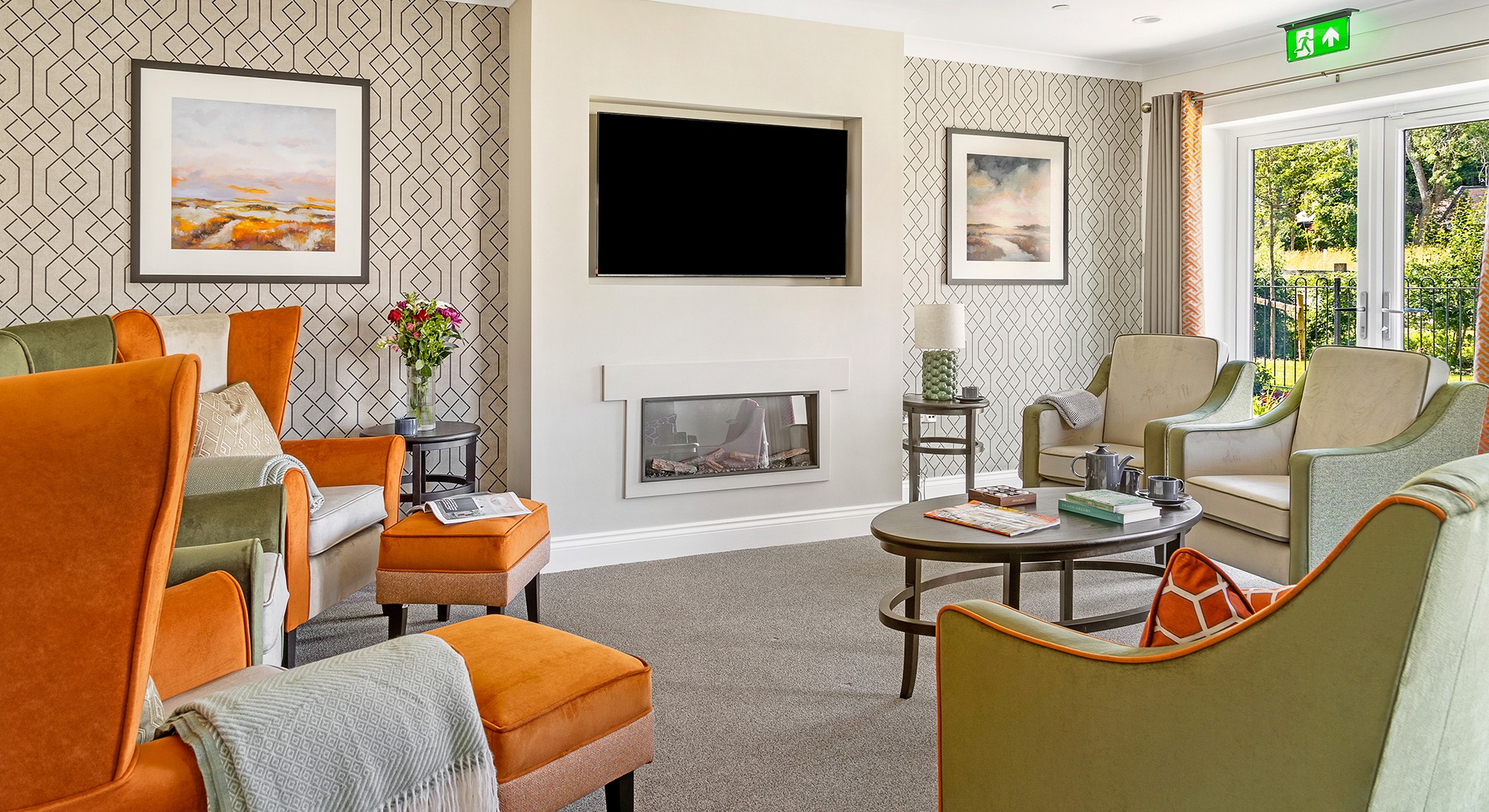 Large living room at Moorhill Care Home with multiple chairs arranged facing a TV and a cozy fireplace