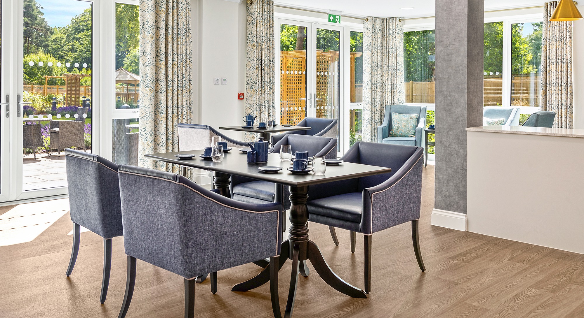 Dining room at Moorhill Care Home with tables set for residents and French doors opening to garden views