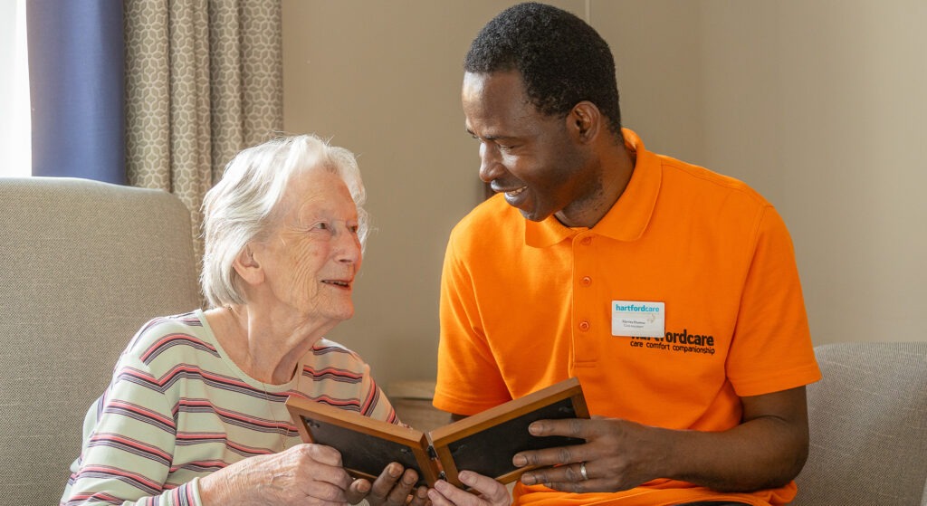 Friendly care assistant and elderly resident smiling and talking at Malden House Care Home in Sidmouth Devon