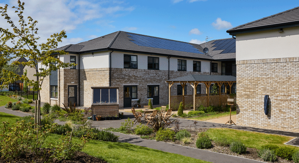 Landscaped gardens at Cotswolds Rise Care Home in Swindon featuring greenery, walking paths, and seating areas