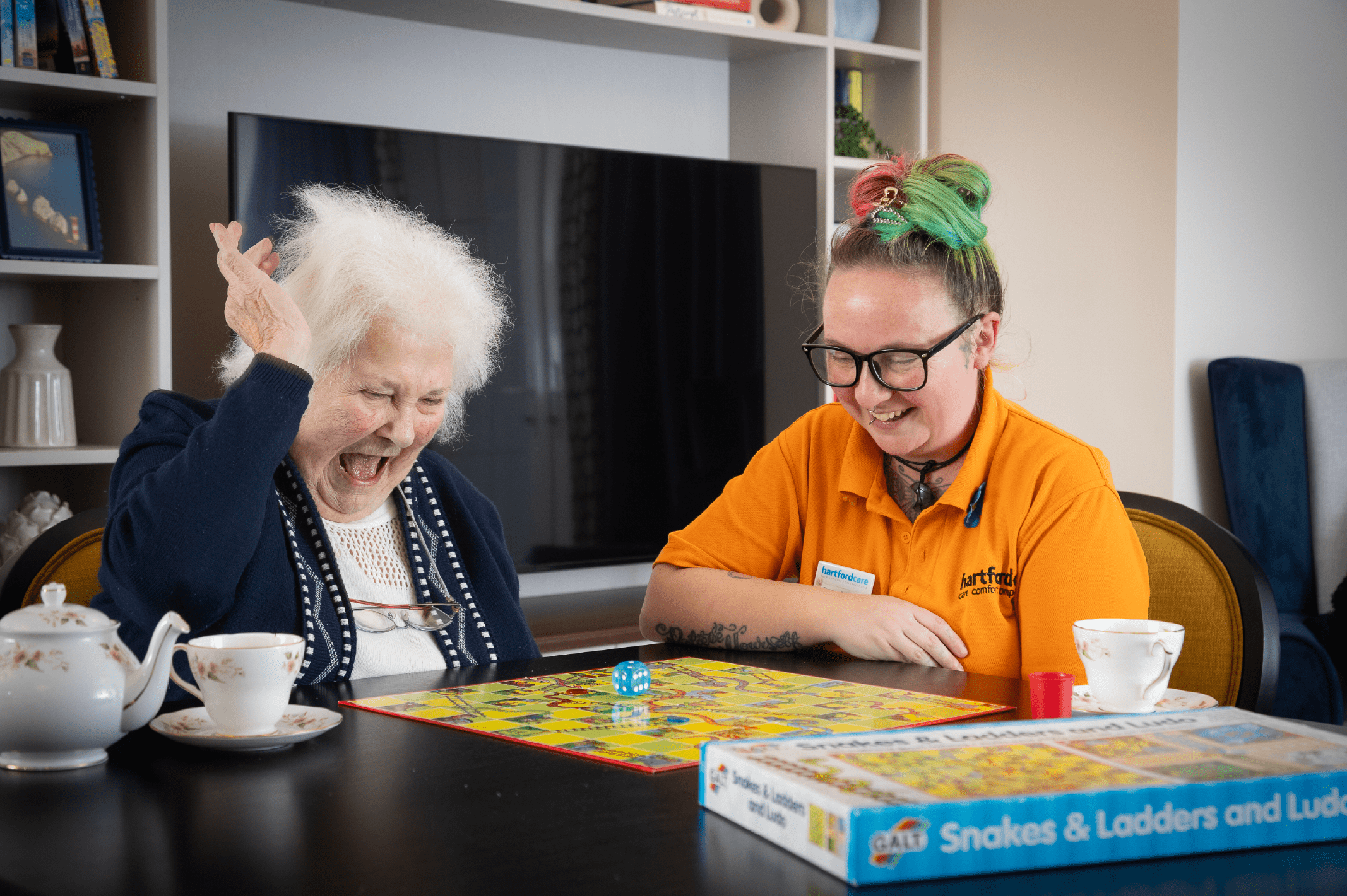 Resident and carer playing snakes and ladders at Hawkinge House Care Home
